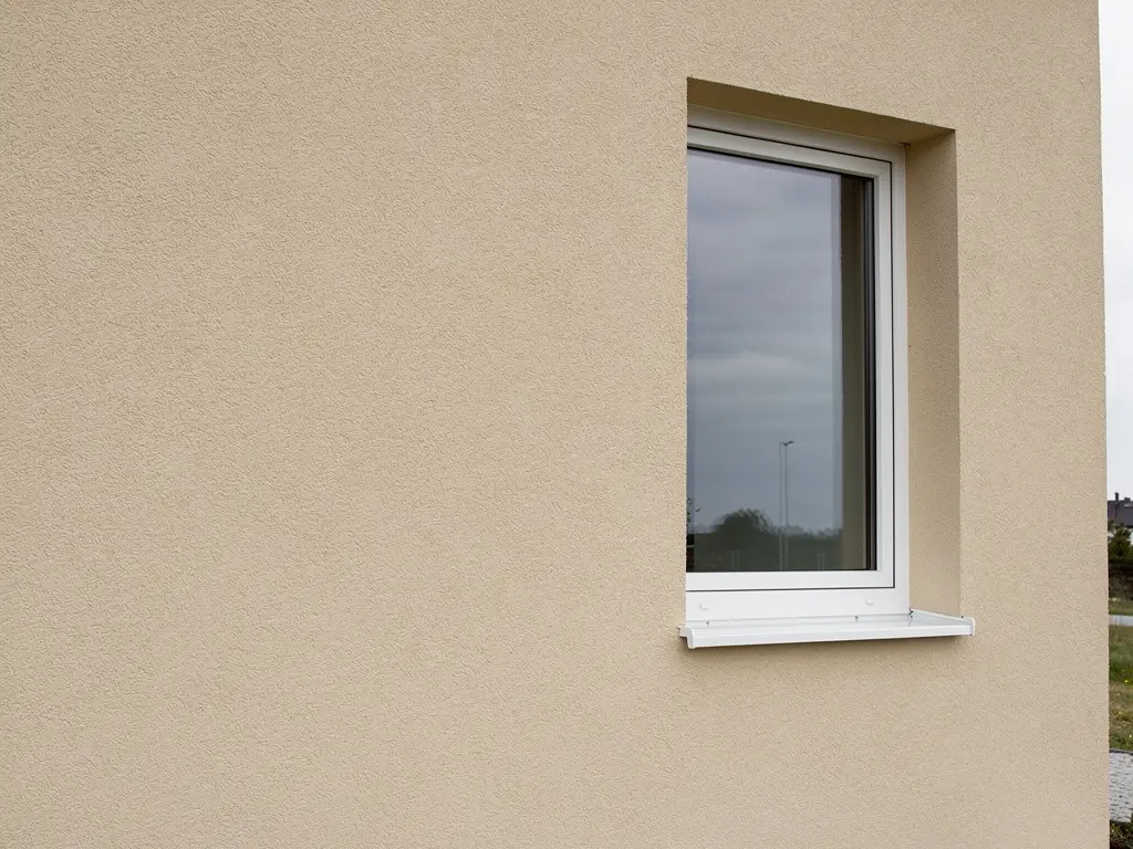 Mur de maison isolé par l'extérieur et recouvert d'un enduit beige taloché